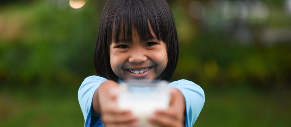 Little girl drinking milk in the park